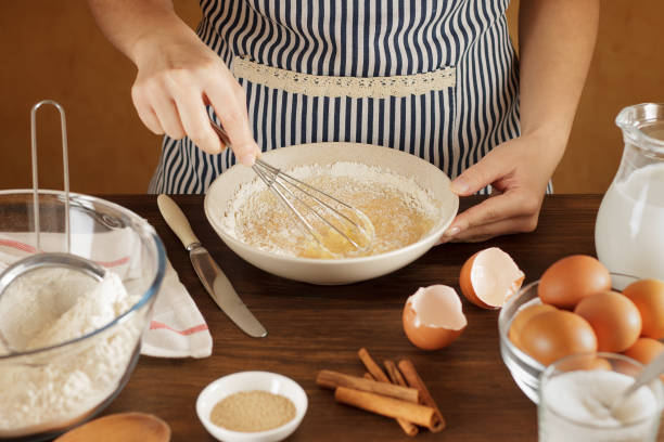 Woman mixes flour with eggs and milk in ceramic bowl on the kitchen. stock photo