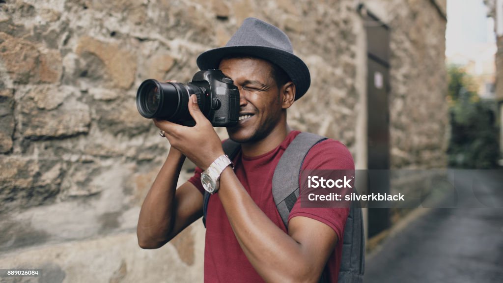Photo prise d’africaine touristique heureux sur son appareil photo reflex numérique. Jeune homme voyageant en Europe - Photo de Hommes libre de droits