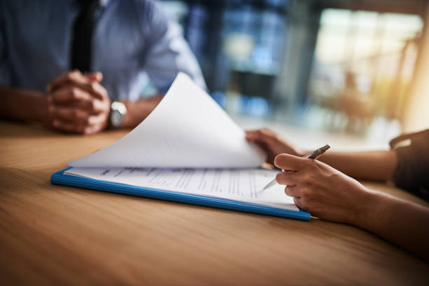 Combing through the fine print Cropped shot of a man and woman completing paperwork together at a desk signing stock pictures, royalty-free photos & images