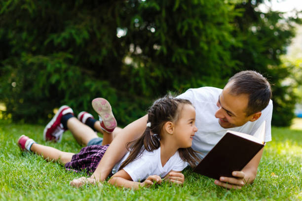 istock Happy father and child reading a book in nature 889037220