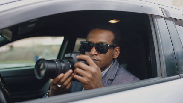 istock Private detective man sitting inside car and photographing with dslr camera 889038752