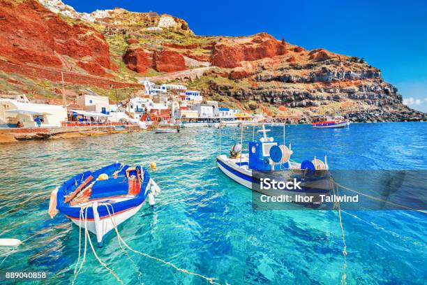Greece Breathtaking Beautiful Landscape Of Two Fishing Boats Anchored To Quay In Fascinating Blue Water At The Amazing Old Port Panorama In Oia Ia Village On Santorini Greek Island In Aegean Sea Stock Photo - Download Image Now