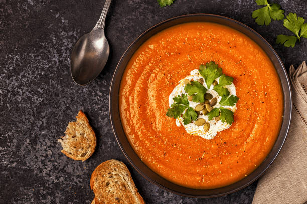 istock Pumpkin and carrot soup with cream, seeds and parsley. 889062376