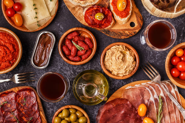 istock Typical spanish tapas concept. Concept include slices jamon, chorizo, sausage, bowls with olives, tomatoes, anchovies,  mashed chickpeas, cheese. 889062802