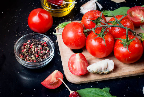 istock Black rustic tabletop with branch of tomatoes and herbs, top view 889094930