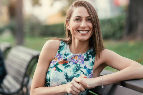 Portrait of a beautiful woman sitting on a bench in the park.