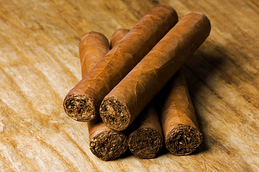Set of Cuban cigars lying on an old wooden table board