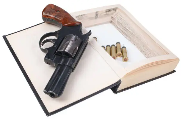 Photo of Revolver gun with cartridges hidden in a book