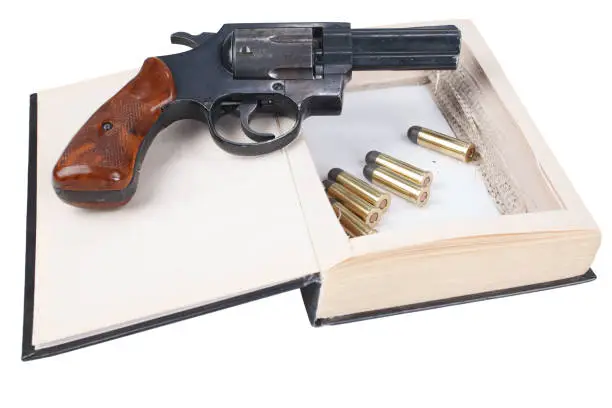 Photo of Revolver gun with cartridges hidden in a book