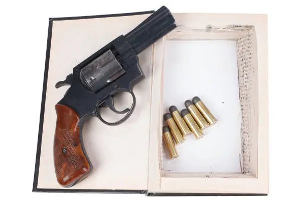 Photo of Revolver gun with cartridges hidden in a book
