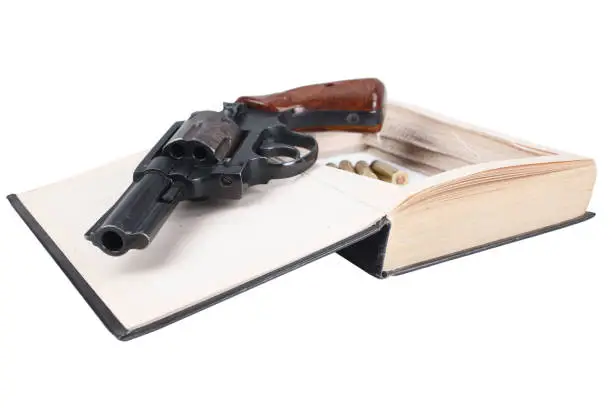 Photo of Revolver gun with cartridges hidden in a book