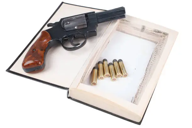 Photo of Revolver gun with cartridges hidden in a book