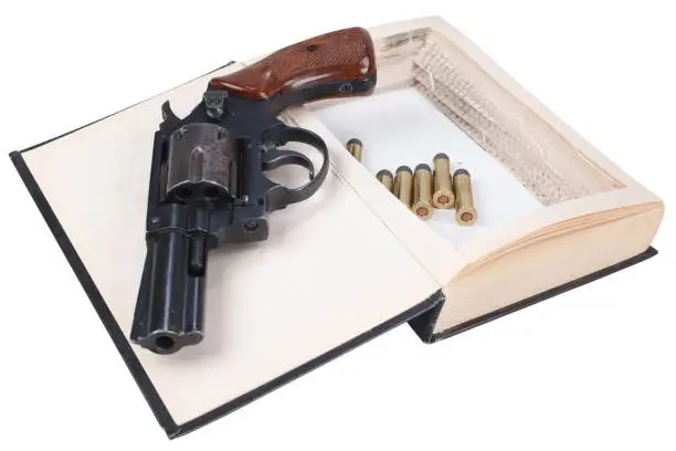 Photo of Revolver gun with cartridges hidden in a book