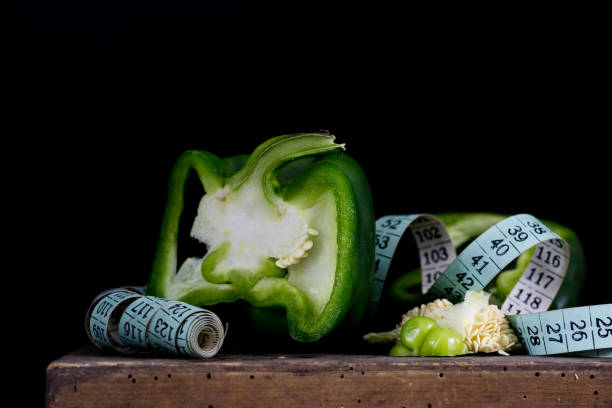 istock Cut out green peppers on old kitchen table and measure tailor. Vegetables in the old kitchen with measure. Black background. 889115004