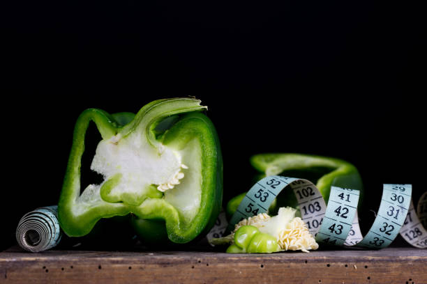 istock Cut out green peppers on old kitchen table and measure tailor. Vegetables in the old kitchen with measure. Black background. 889115088
