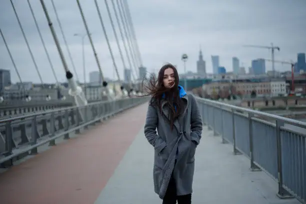 View on the bridge with young woman walking back during the windy weather in Warsaw city, Poland