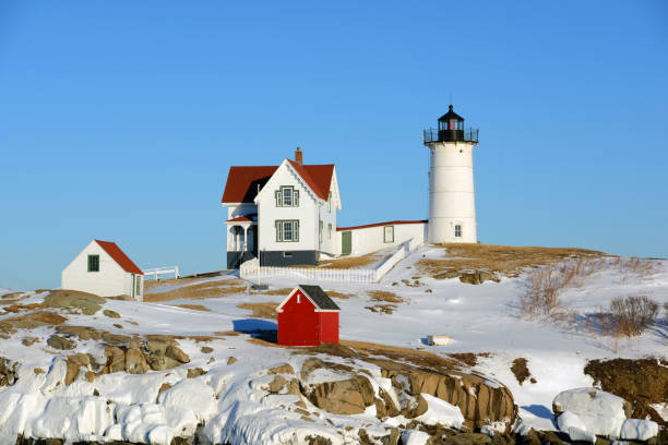 маяк мыса неддик в олд-йорк-виллидж зимой, штат мэн, сша - maine lighthouse winter ice стоковые фото и изображения