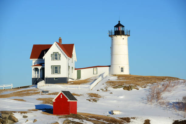 маяк мыса неддик в олд-йорк-виллидж зимой, штат мэн, сша - maine lighthouse winter ice стоковые фото и изображения
