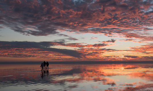 Happy young family having fun running on salt lake at sunset