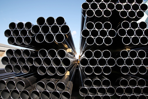 stack of industrial steel tubes against clear blue sky