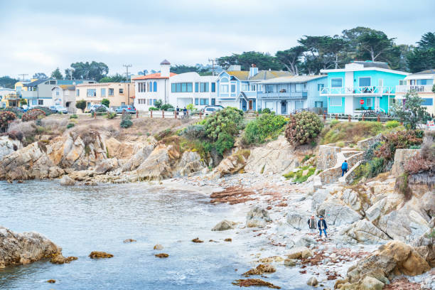 Waterfront in Pacific Grove neighborhood in Monterey California People walk on the beach in Perkins Park in the Pacific Grove neighborhood of Monterey, California, USA on an overcast day. city of monterey california stock pictures, royalty-free photos & images