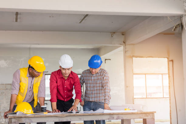 istock Foreman, labor and engineer as discussing about their project with blueprint with safety helmet on table at old buildings in their job site. 889204574