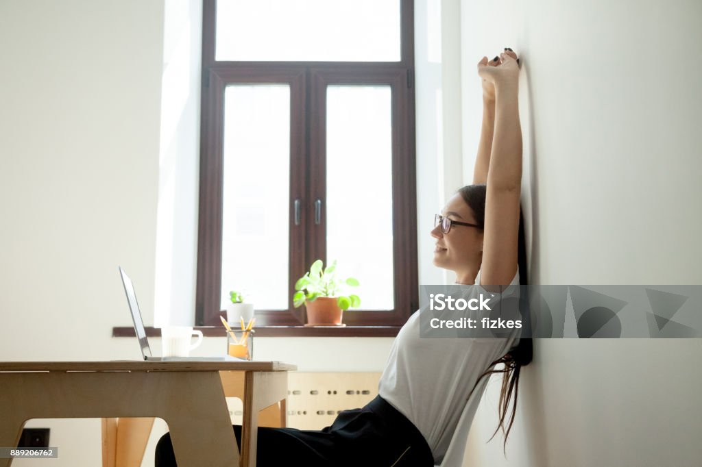 Atractivo joven empresaria relajante, estiramientos en el escritorio en la oficina en casa - Foto de stock de Buena postura libre de derechos