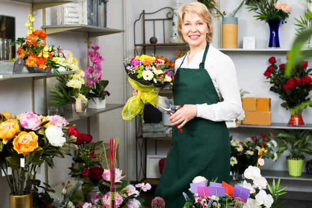 istock Florist in apron holding scissors and fixing flowers 889208976