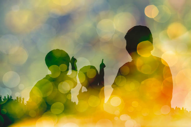 silhouette of mother and two kids on bokeh abstract in yellow background - kd imagens e fotografias de stock