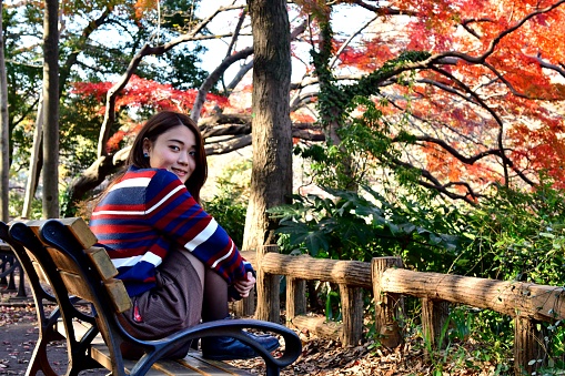 Young Japanese woman is trying to make various facial expression, while she enjoys autumn colors in Inokashira Park, located in the suburbs of  Tokyo. 