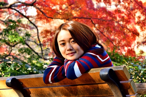 Young Japanese woman is trying to make various facial expression, while she enjoys autumn colors in Inokashira Park, located in the suburbs of  Tokyo. 