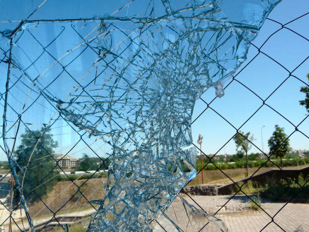 istock Broken Window Glass Seen Through Metal Grid Fence 889289384