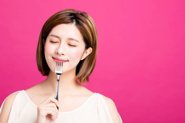 joven mujer sosteniendo la bifurcación y disfrutar de comida sabrosa - tasting women eating expressing positivity fotografías e imágenes de stock