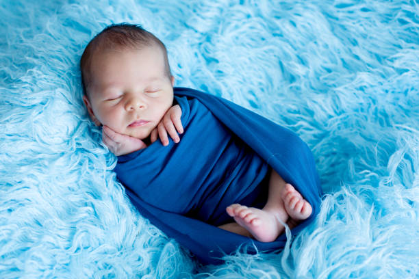 istock Cute baby boy, peacefully sleeping wrapped in blue wrap 889323560