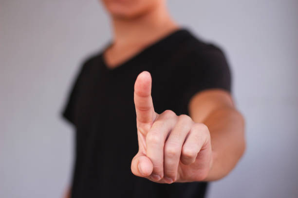 istock A young guy in a black t-shirt pressing on the screen. On grey background. 889362434