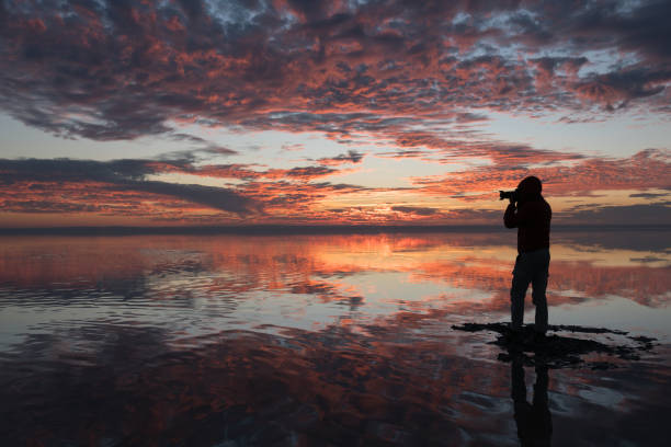 Photographer  having fun walking on salt lake at sunset Photographer  having fun walking on salt lake at sunset beautiful multi colored tranquil scene enjoyment stock pictures, royalty-free photos & images