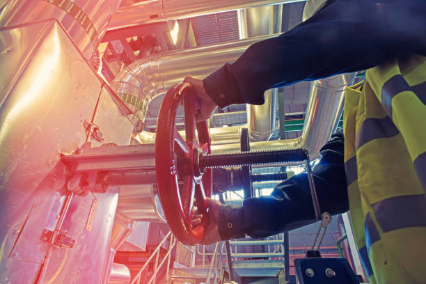 industrial factory worker turning red wheel of valve stock photo
