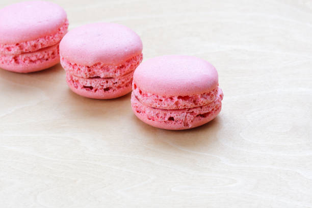 istock pink macaron on wooden background 889408184