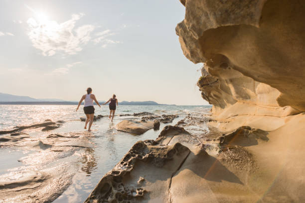 砂岩の海ビーチに沿って実行している 2 人の若い女性 - canadian beach ストックフォトと画像