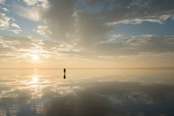 istock Man standing over sunset clouds  on salt lake 889425138
