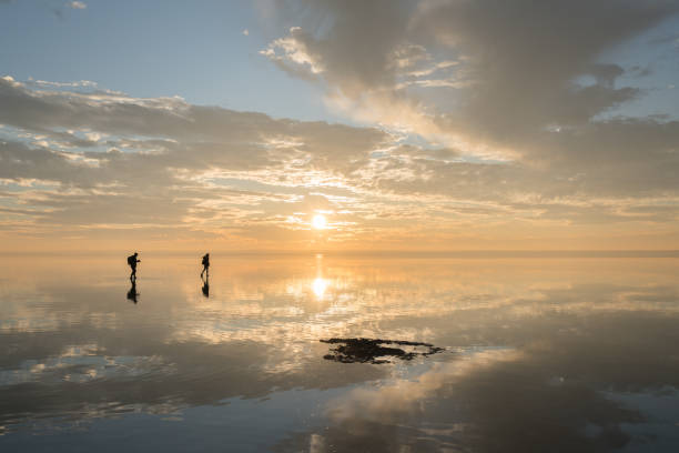 istock Happy young couple having fun walking on salt lake at sunset 889425324