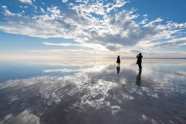 istock Happy young couple having fun walking on salt lake at sunset 889436004