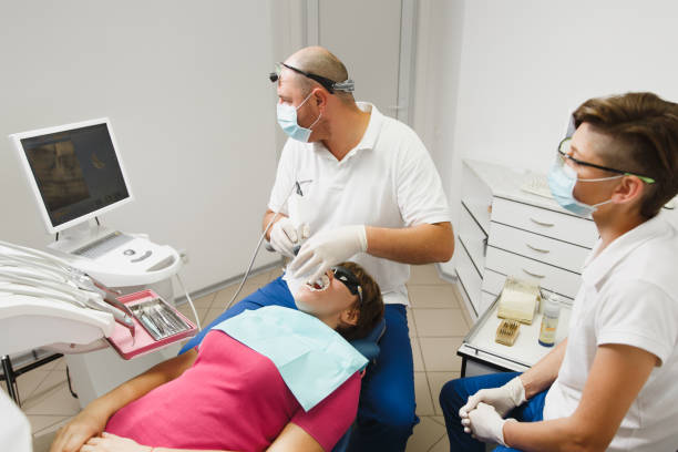 準備とセラミック クラウンをインストールするプロセス。プロの歯科医師とお探しのアシスタント、監視、近代的なツール装備クリニック光オフィスで女性患者の歯を治療します。 - dental light dental equipment hospital professional occupation ストックフォトと画像