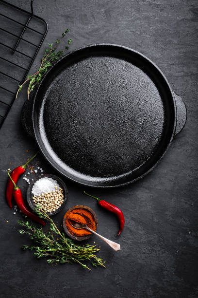 istock Empty cast-iron pan with ingredients for cooking on black background, top view 889436222
