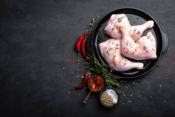 istock Raw chicken quarters, legs in a pan on a dark background. Top view. 889436394