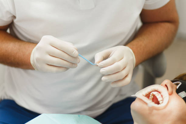 準備とセラミック クラウンをインストール プロセスを閉じます。男性プロの歯科医師は、現代のツール装備クリニック光オフィスで女性患者の歯を治療するのに役立ちます。口を開けて。 - dental light dental equipment hospital professional occupation ストックフォトと画像