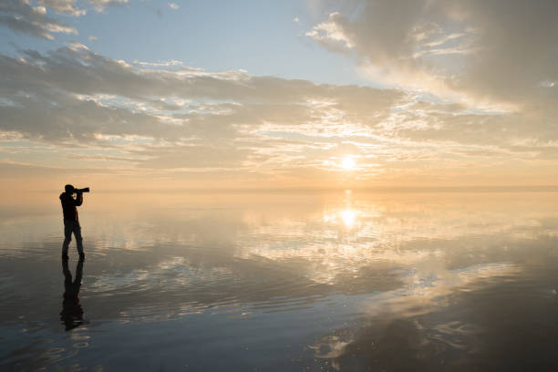 istock Photographer  having fun walking on salt lake at sunset 889440890