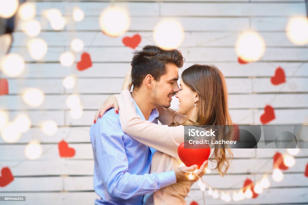 Young couple on Valentine's Day. Young couple on Valentine's Day. A loving couple hugs against a background of glowing garlands. Couple - Relationship Stock Photo