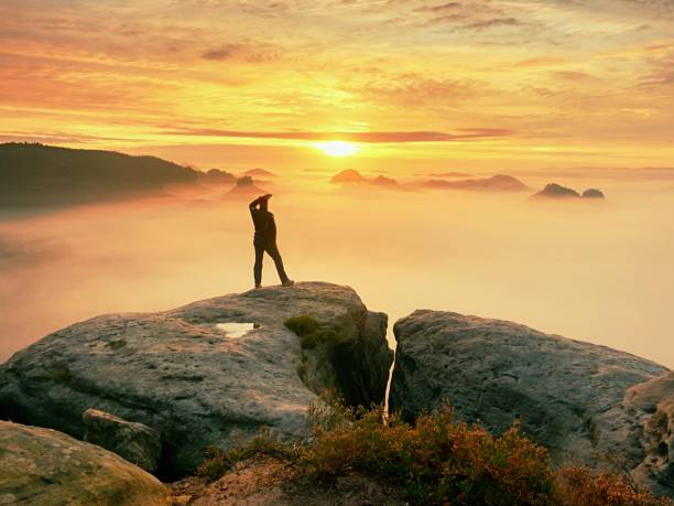 istock Photographer silhouette above a clouds sea, misty mountains 889446394