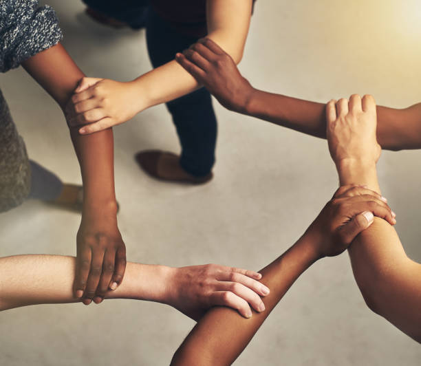 There is strength in unity High angle shot of a group of unrecognizable people holding one another's arms to form a circle arm in arm stock pictures, royalty-free photos & images